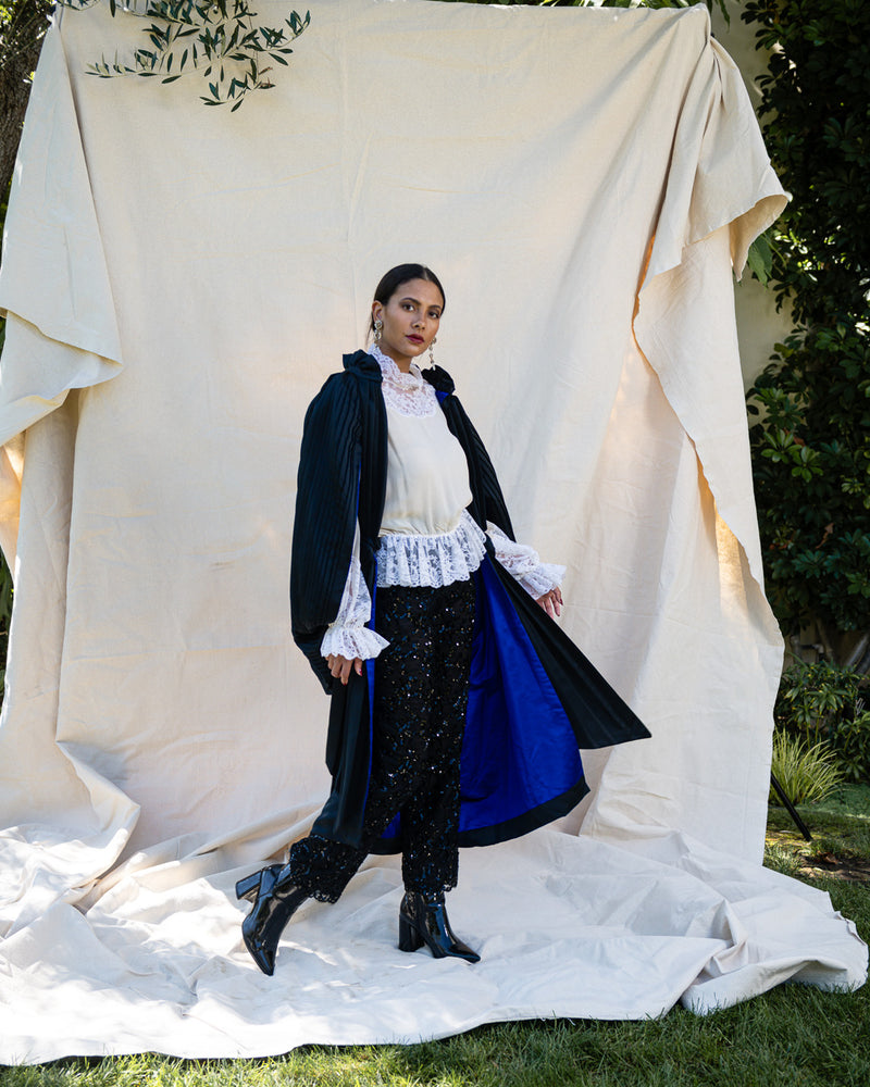 Pleated Cocoon Coat by Calderon on model in front of canvas 