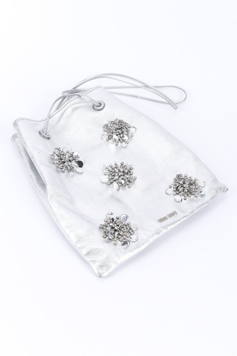 Miu Miu Metallic Drawstring Bag 3/4 view laid flat on white backdrop @Recessla