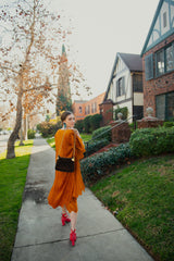 Girl in orange outfit with Gucci Monogram Chenille Bag from Recess on sidewalk